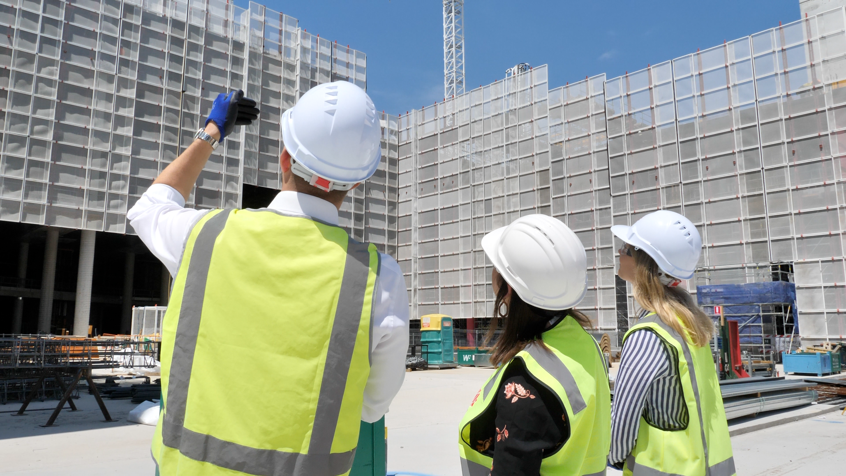 Three people in hi-vis vests on a construction site