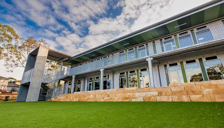 Exterior of two story building with sandstone walls and landscaping